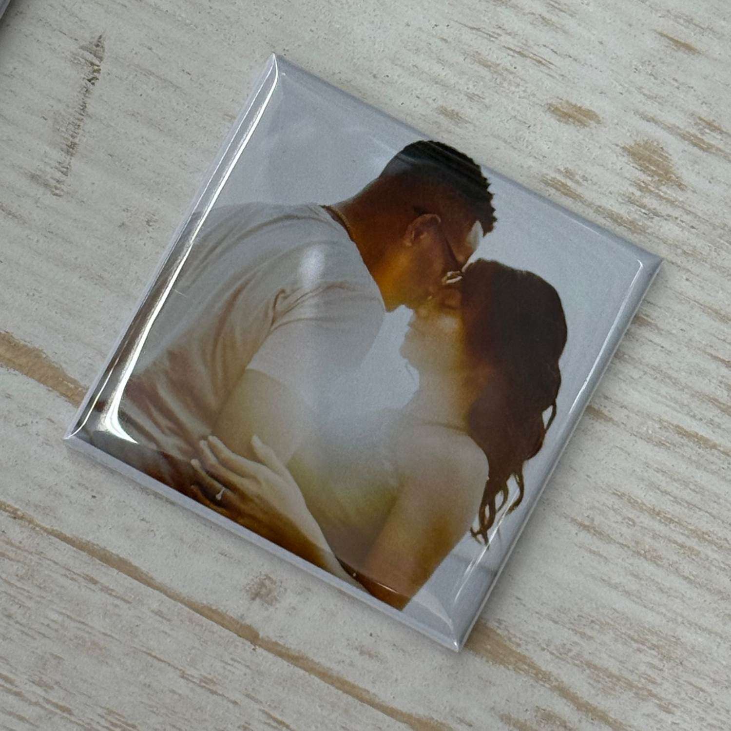 photo magnet with a couple embracing on a wooden surface.