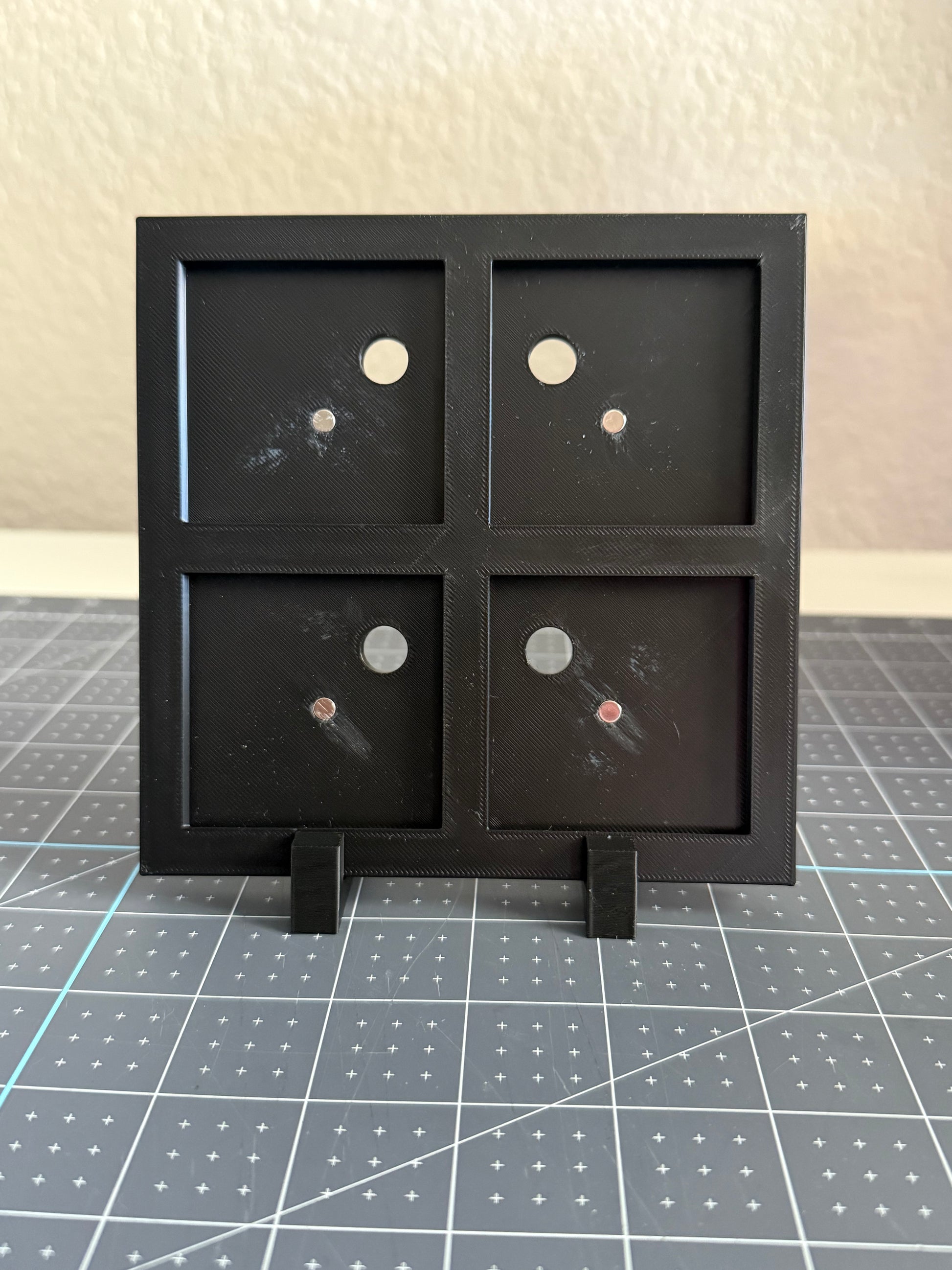 Black display stand with four square compartments for magnets.